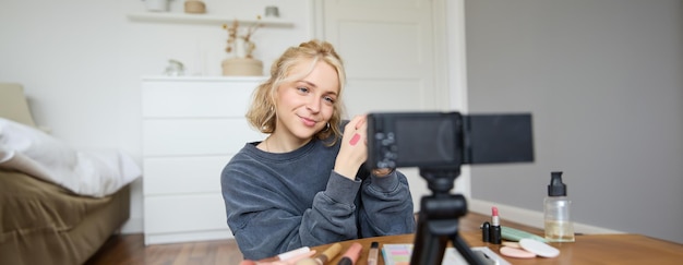 Gratis foto afbeelding van een jonge stijlvolle vrouwelijke blogger die een beauty lifestyle video opneemt van haar het kiezen van de beste lippenstift