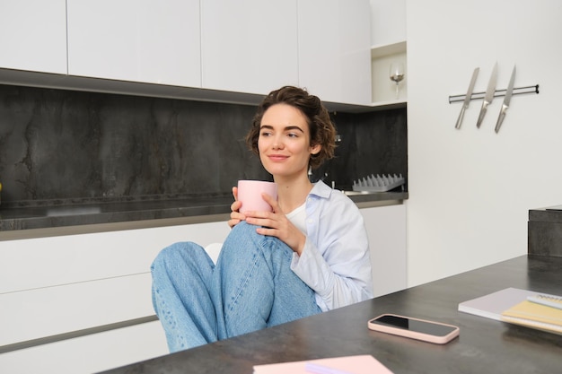Afbeelding van een jonge volwassen vrouw met een kopje koffie, een meisje dat thuis ontspannen drinkt, thee heeft, heeft een pauze van het werk