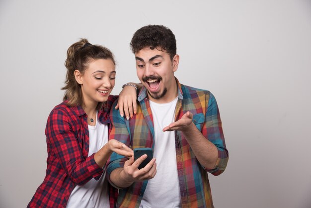 Afbeelding van een jonge vrouw die naar de mobiele telefoon van haar man kijkt.