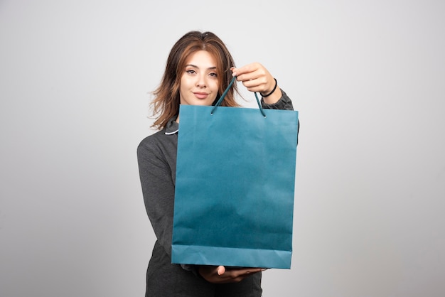 Afbeelding van een jonge vrouw die naar een winkeltas kijkt.