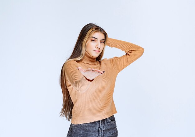 Afbeelding van een jonge vrouw model in bruine trui staande en poseren.