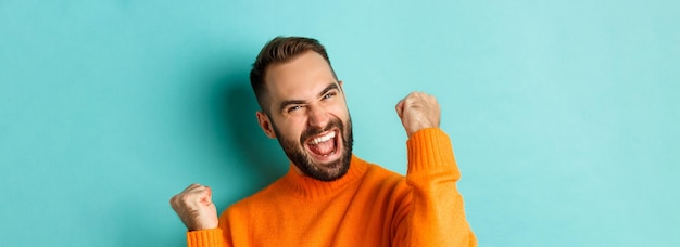 Gratis foto afbeelding van een knappe, opgeluchte man die voldoening voelt en zich verheugt over het winnen of het maken van een vuist