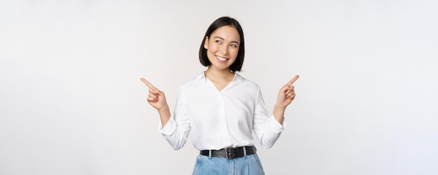 Afbeelding van een mooie aziatische vrouw die met de vingers naar links en rechts wijst en een beslissing neemt met twee variantenkeuzes die op een witte achtergrond staan