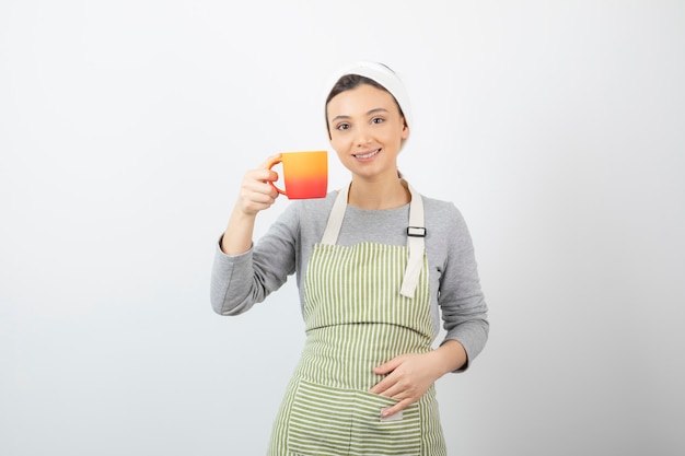 Afbeelding van een mooie jonge vrouw in schort met een kopje