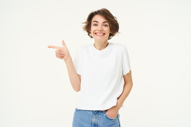 Afbeelding van een schattige vrouw met een gelukkige glimlach die naar links wijst en een advertentie over wit toont