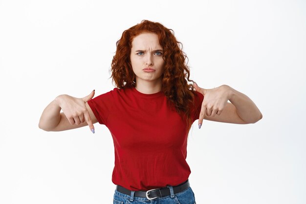 Afbeelding van een teleurgestelde en verdrietige vrouw die klaagt over oneerlijke dingen die mokkend en fronsend naar beneden wijzen naar een banner die tegen een witte achtergrond staat