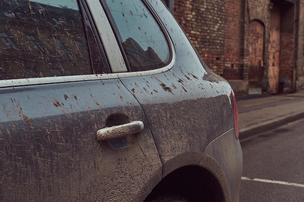 Afbeelding van een vuile auto na een off-road reis. Staat tegen een bakstenen muur in het oude gedeelte van de stad.