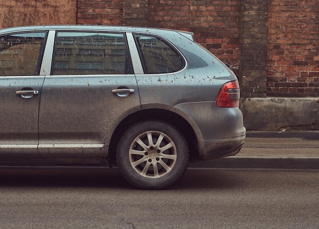 Afbeelding van een vuile auto na een off-road reis. Staat tegen een bakstenen muur in het oude gedeelte van de stad.