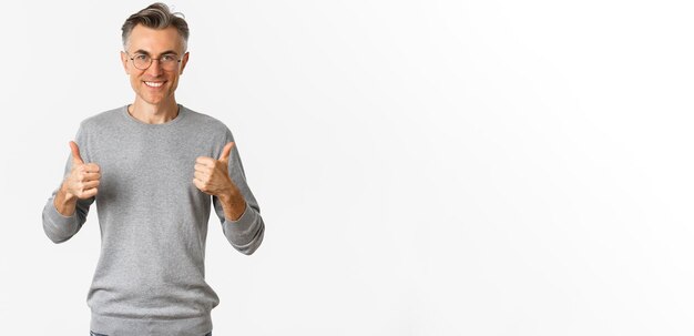 Afbeelding van een zelfverzekerde en tevreden man van middelbare leeftijd die lacht, blij met duim omhoog in grijze sweater
