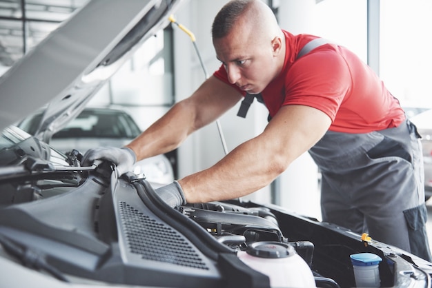 Afbeelding van gespierde autodienstmedewerker die voertuig repareert.