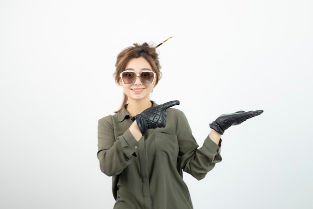 Afbeelding van jonge schattige vrouw in glazen en zwarte handschoenen permanent. Hoge kwaliteit foto