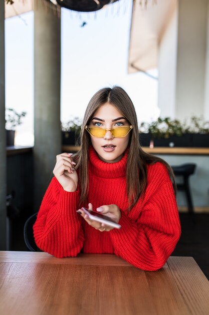 Afbeelding van jonge vrouw die sms leest aan de telefoon in café