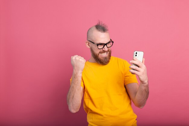 Afbeelding van schreeuwende jonge bebaarde knappe man vieren overwinning en succes erg opgewonden op roze