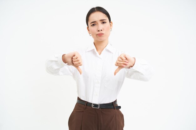 Afbeelding van teleurgestelde vrouwelijke manager toont duim omlaag en fronst met afkeuring witte achtergrond