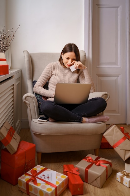 Afbeelding van tevreden aardige vrouw met creditcard met kopie ruimte met behulp van laptop