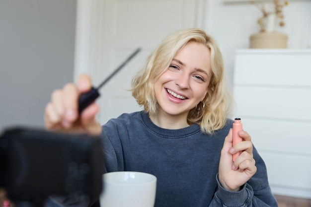 Afbeelding van vrolijke mooie jonge lifestyle blogger vrouw die op de vloer zit en een video opneemt over