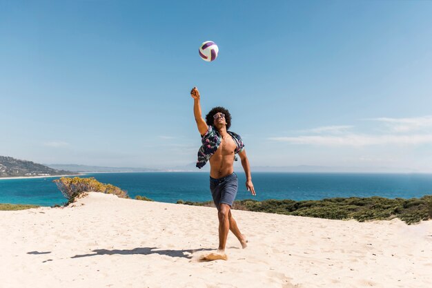 African American man spelen met de bal op het strand