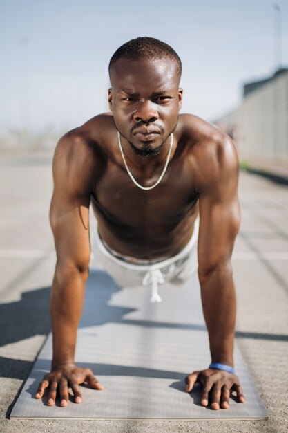 African American man staat op zijn armen op de grond doen push-ups