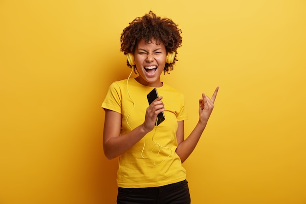 African American vrouw, gekleed in geel T-shirt en koptelefoon