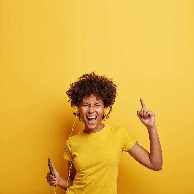 African American vrouw, gekleed in geel T-shirt en koptelefoon