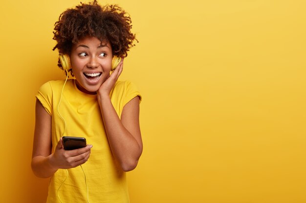 African American vrouw, gekleed in geel T-shirt en koptelefoon