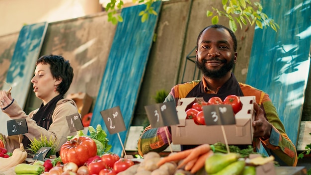 Gratis foto afrikaans-amerikaanse boer die een doos tomaten voor de camera presenteert