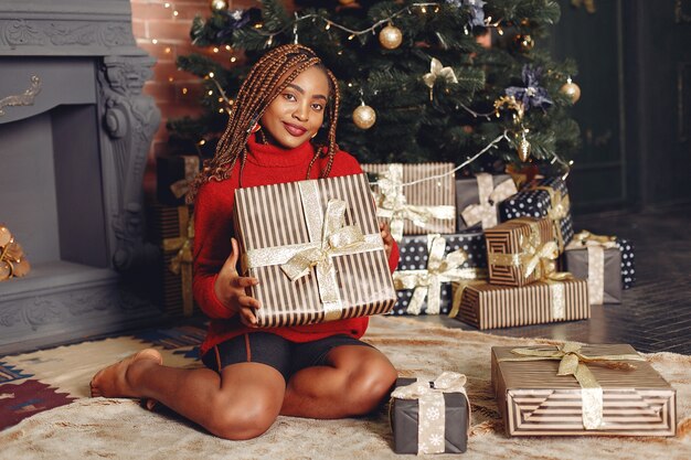 Afrikaans meisje in een kerstversiering / vrouw in een rode trui. Nieuwjaar concept.