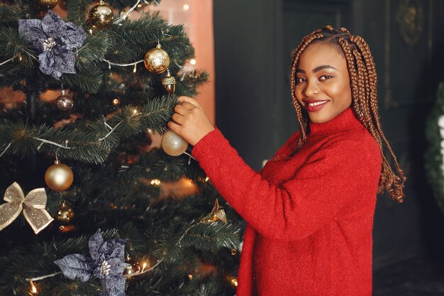 Afrikaans meisje in een kerstversiering / vrouw in een rode trui. Nieuwjaar concept.