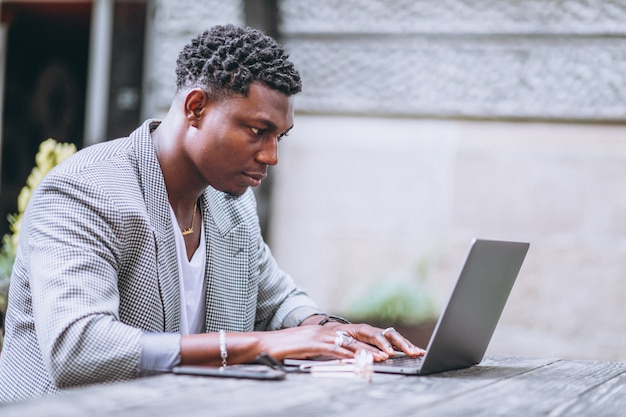 Gratis foto afrikaanse amerikaanse bedrijfsmens die laptop in een koffie met behulp van