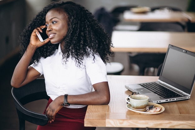 Afrikaanse Amerikaanse bedrijfsvrouw die op telefoon in een koffie spreekt