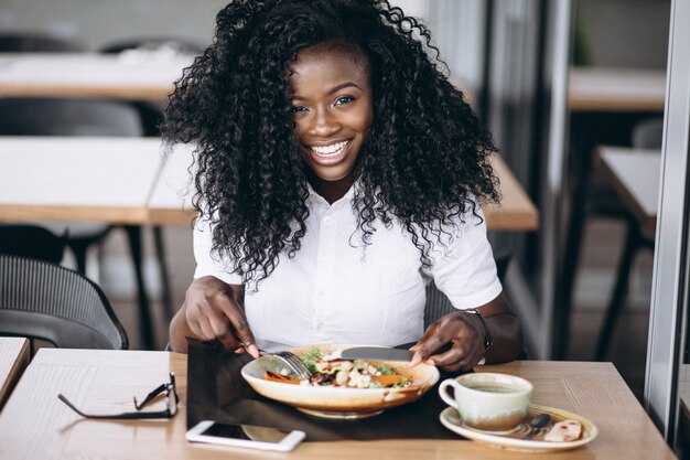 Afrikaanse Amerikaanse bedrijfsvrouw die salade in een koffie eet