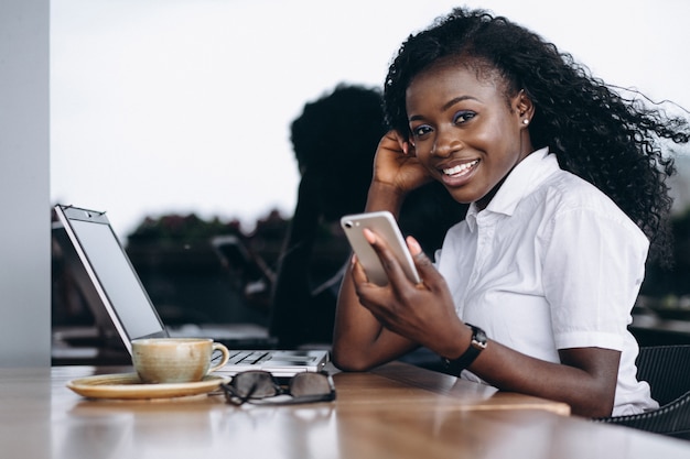 Afrikaanse Amerikaanse zakenvrouw met computer en telefoon in een café