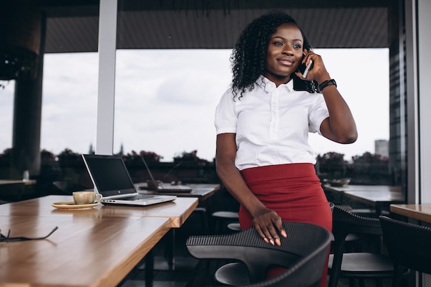 Afrikaanse Amerikaanse zakenvrouw met computer en telefoon in een café