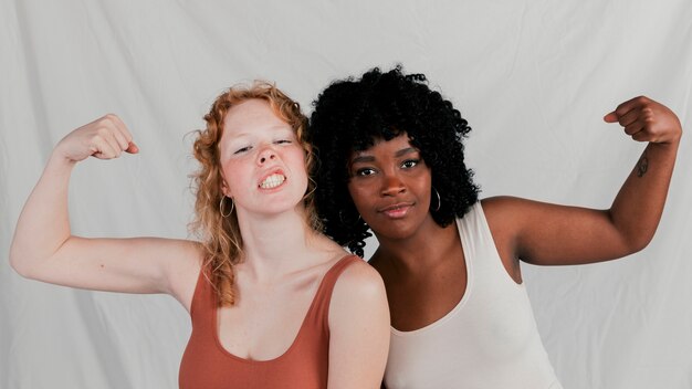 Afrikaanse en blonde jonge vrouwen die hun vuist balanceren die camera bekijken