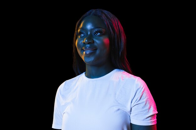 Afrikaanse jonge dames portret op donkere muur in neon concept van menselijke emoties gezichtsuitdrukking jeugd verkoop advertentie