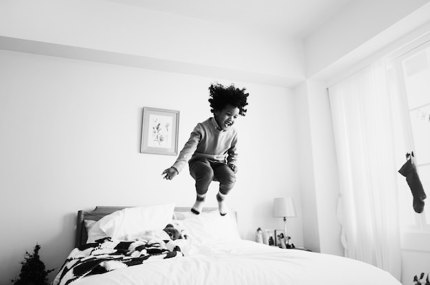 Afrikaanse jongen die plezier heeft met springen op het bed