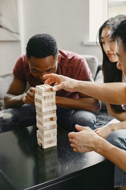 Gratis foto afrikaanse jongen en aziatisch stel die jenga spelen speel bordspel in vrije tijd