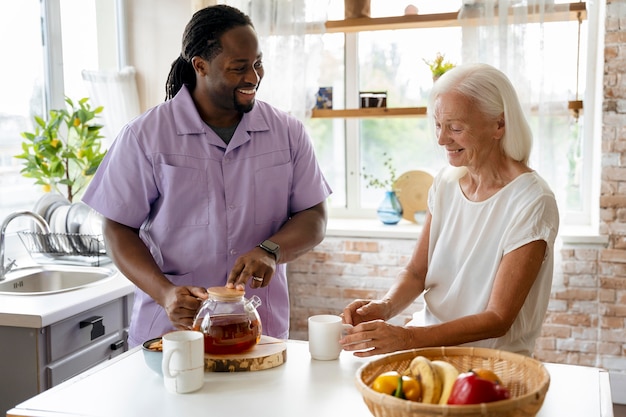 Afrikaanse maatschappelijk werker die een oudere vrouw helpt