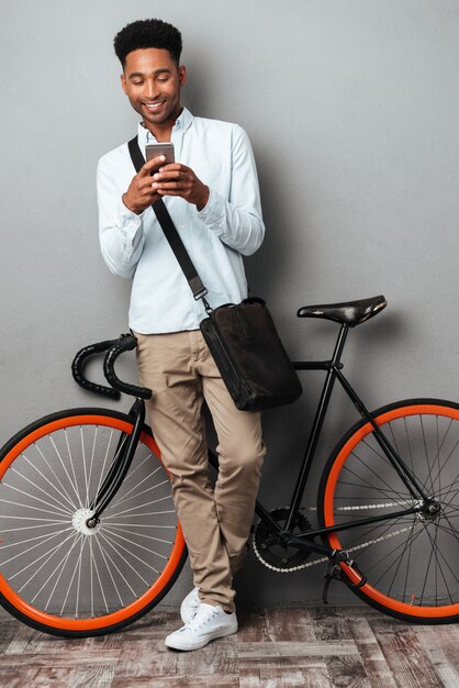 Afrikaanse mens die zich dichtbij fiets bevindt die telefonisch babbelt.
