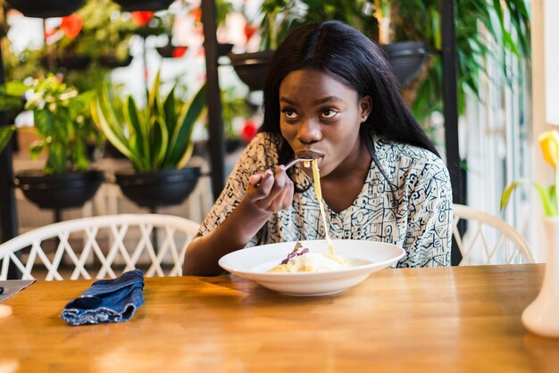 Afrikaanse mooie vrouw is pasta eten en wijn drinken in het Italiaanse restaurant