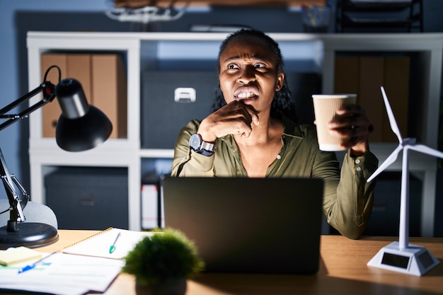 Afrikaanse vrouw die 's nachts met een computerlaptop werkt en zich zorgen maakt over een vraag, bezorgd en nerveus met de hand op de kin