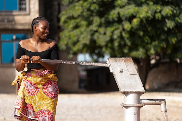 Afrikaanse vrouw die water in een recipiënt giet