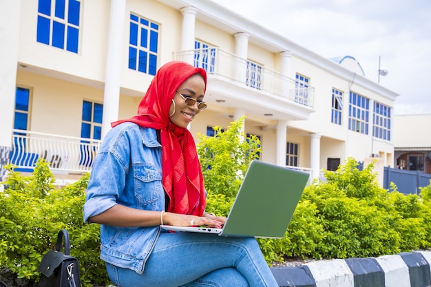 Afrikaanse vrouw gelukkig online browsen met behulp van een laptop zittend in een park