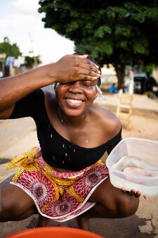 Afrikaanse vrouw giet water in een ontvanger buitenshuis Gratis Foto