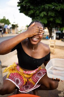Afrikaanse vrouw giet water in een ontvanger buitenshuis