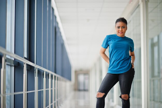 Afrikaanse vrouw in blauw t-shirt poseerde samen binnen