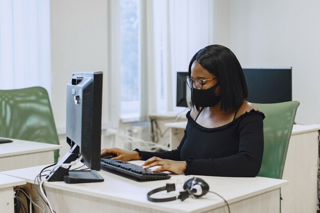 Afrikaanse vrouwenzitting in computerwetenschapsklasse. Dame met bril. Vrouwelijke studentenzitting bij de computer.