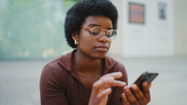 Afro-Amerikaans meisje leest laatste nieuws op smartphone Jonge vrouw
