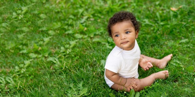 Afro-amerikaanse baby op het groene grasveld in de zomerbannerruimte voor tekst