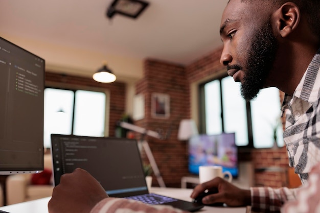 Afro-amerikaanse coder die binaire code-interface programmeert, met behulp van css html-script en codering op de computer. mannelijke freelancer-coderingsbeveiligingsserver met softwareontwikkelaarstoepassing.